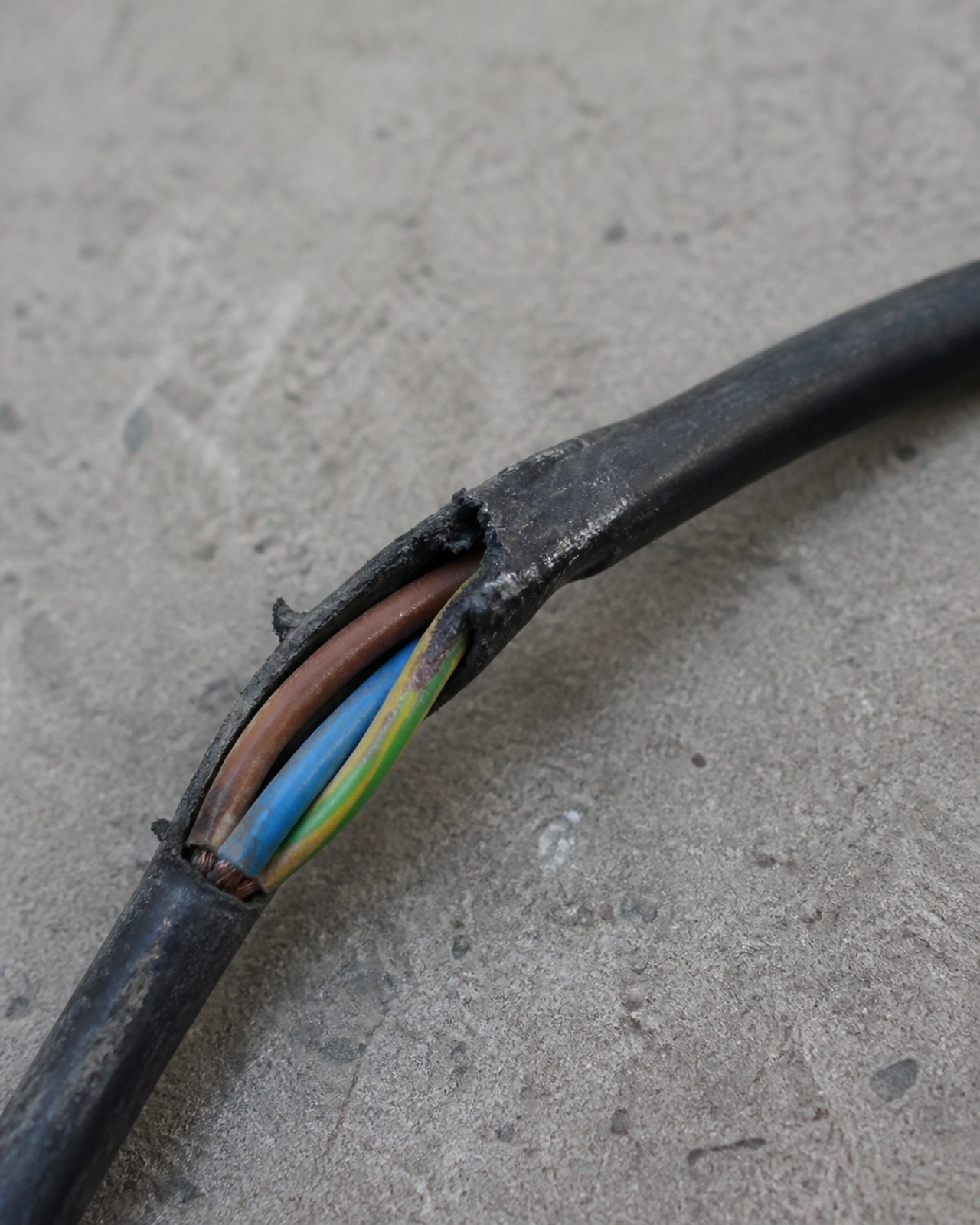 Close-up of a frayed electrical cable with exposed wires, illustrating a critical failure found during a visual safety inspection