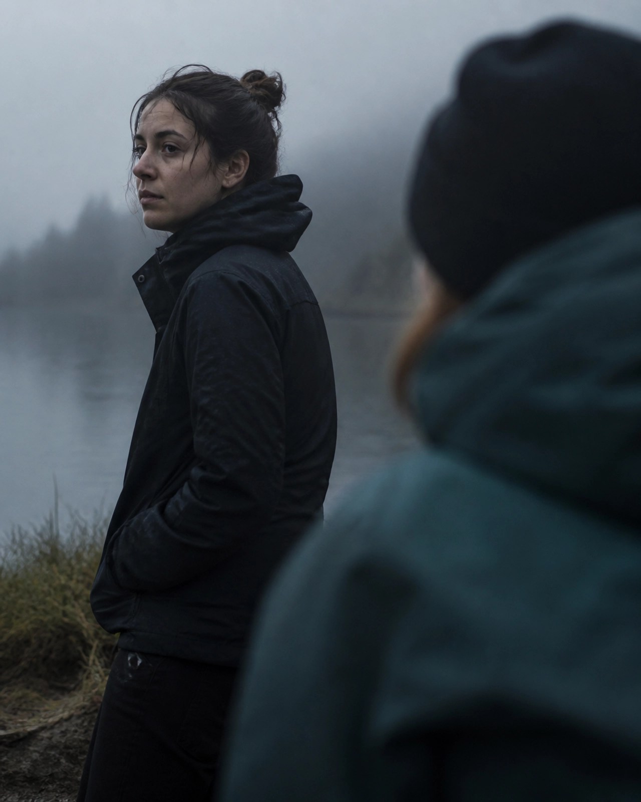 A person sitting in a misty, foggy outdoor environment with a companion nearby