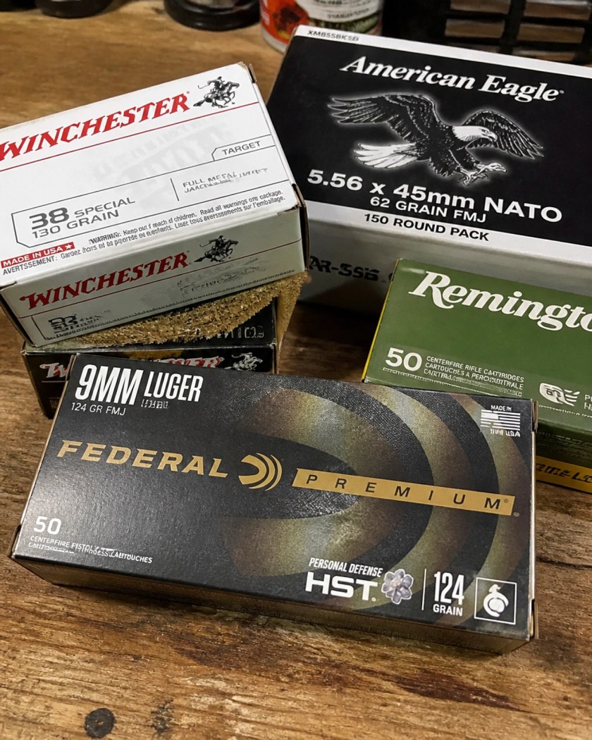 Close up of various centerfire ammunition boxes on a wooden workbench