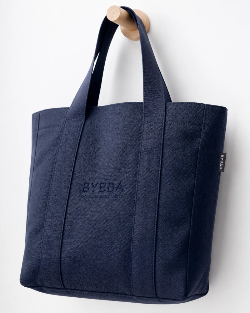A premium navy blue tote bag made from recycled ocean plastic, showcasing the shift toward high-end sustainable merchandise.