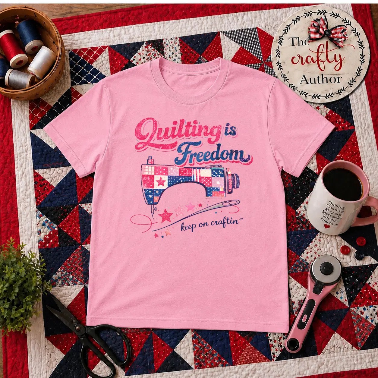 Pink 'Quilting is Freedom' T-shirt styled on a cozy workspace with quilting tools.