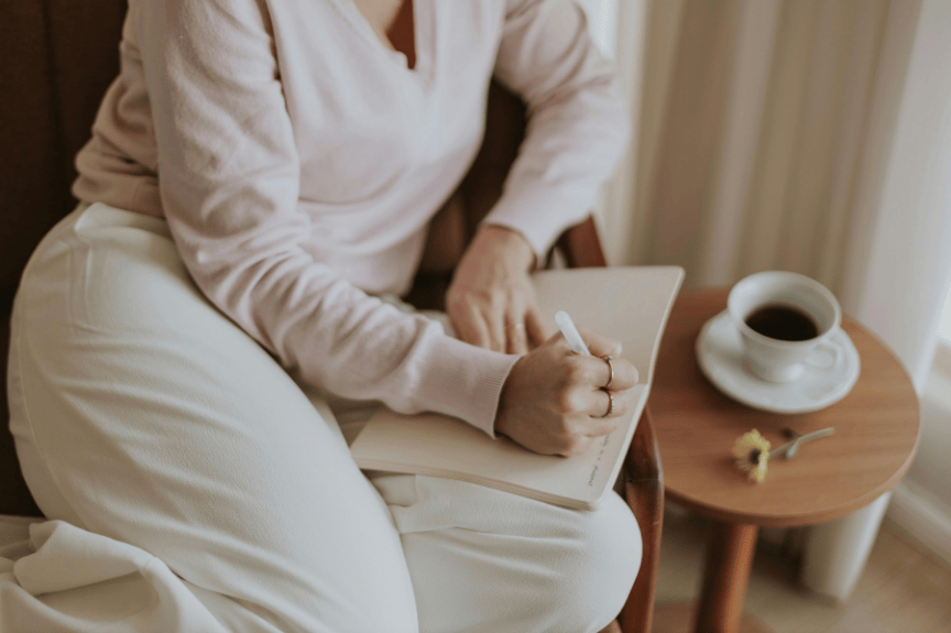 Caregiver writing in a notebook during a quiet reflective moment at home