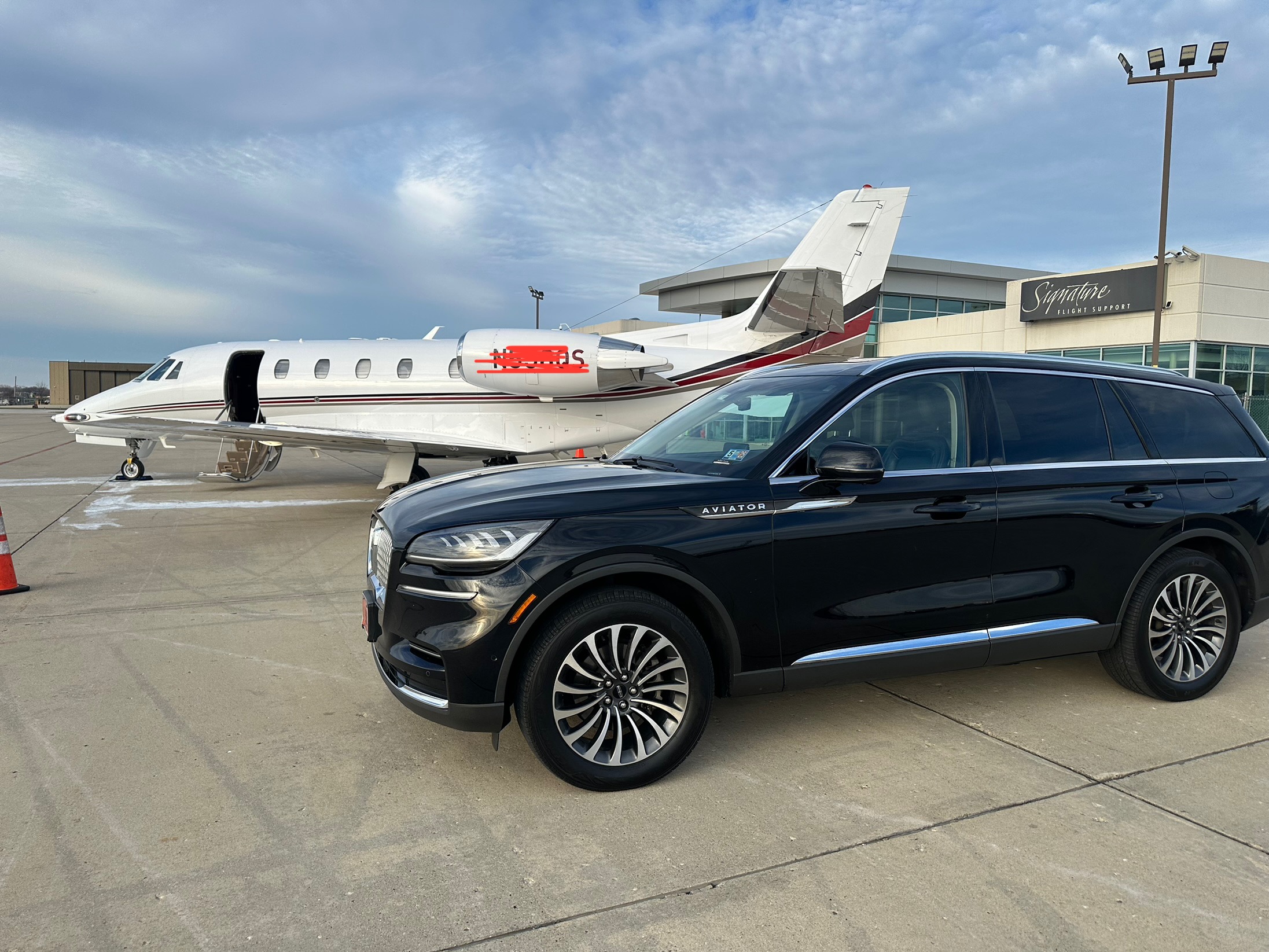 A Lincoln Aviator prepared for a premium airport transfer beside a private aircraft