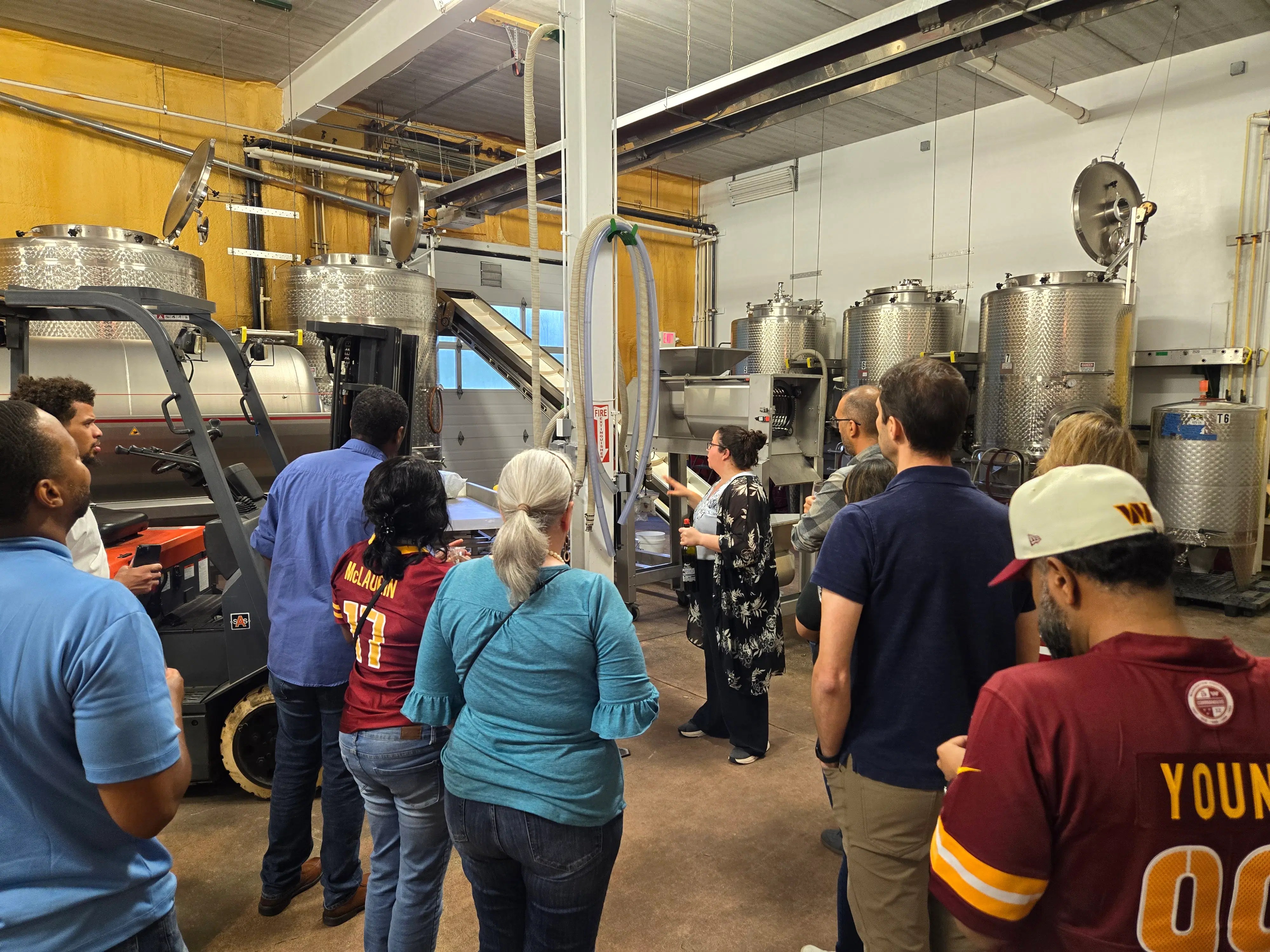 Visitors learning about winemaking equipment during a Vineyard Voyages production facility tour