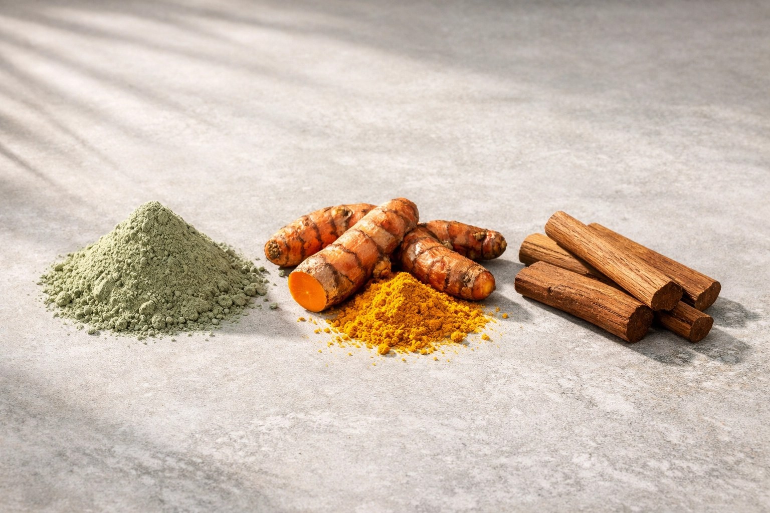 Raw ingredients for the Golden Glow Mask including French green clay powder, turmeric roots, and sandalwood sticks.