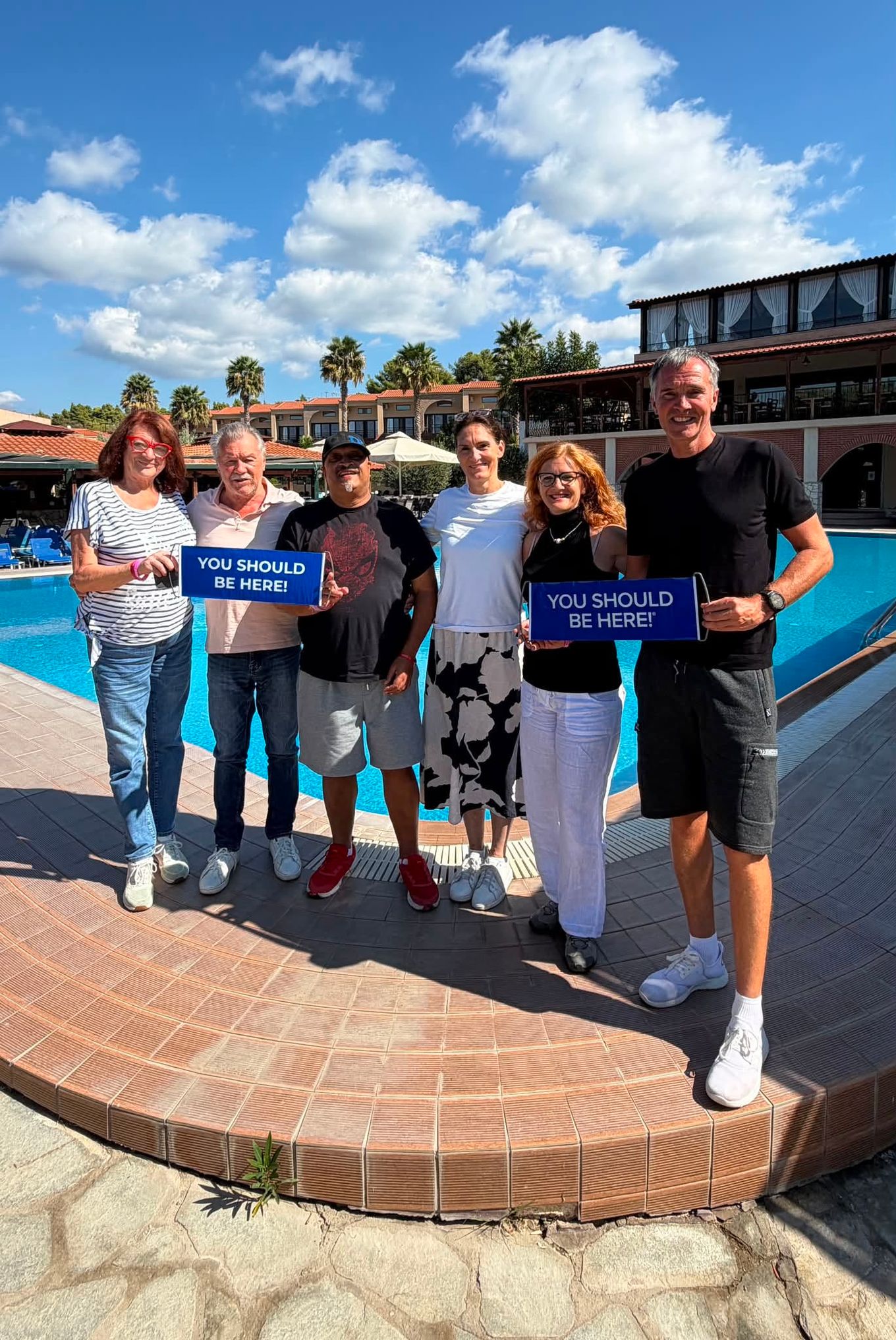 DreamTrips members holding blue banners beside a resort pool