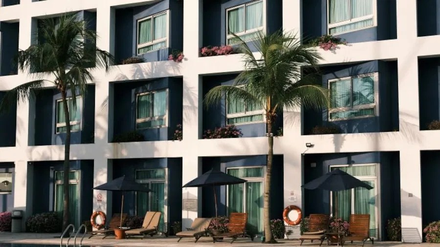 Modern resort property featuring poolside lounge chairs and palm trees