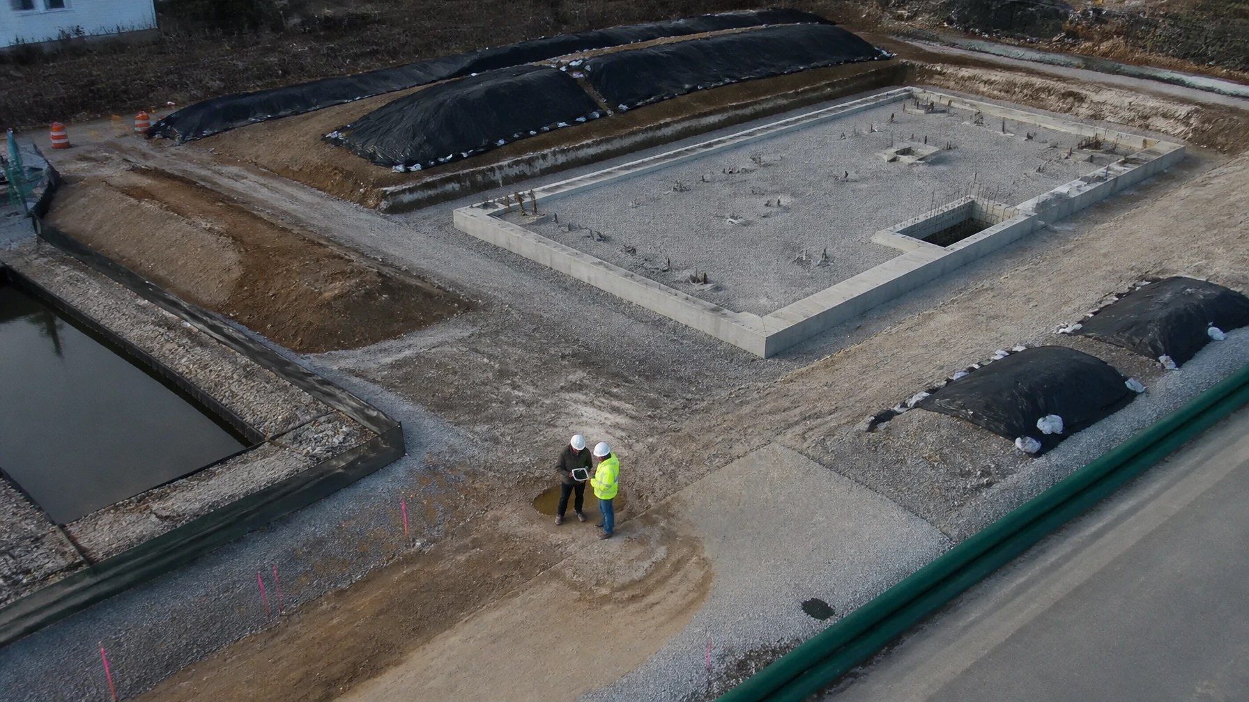 Aerial view of a managed brownfield redevelopment site with excavation, clean fill, stormwater controls, and foundation work