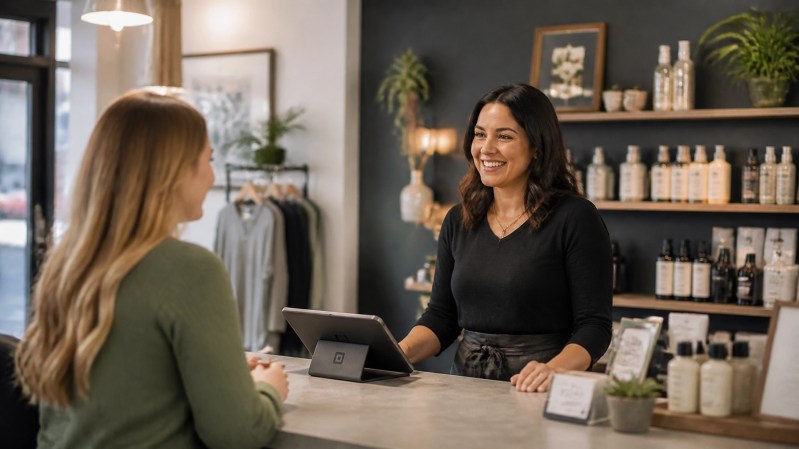 A smiling local business owner interacting with a customer in a modern storefront