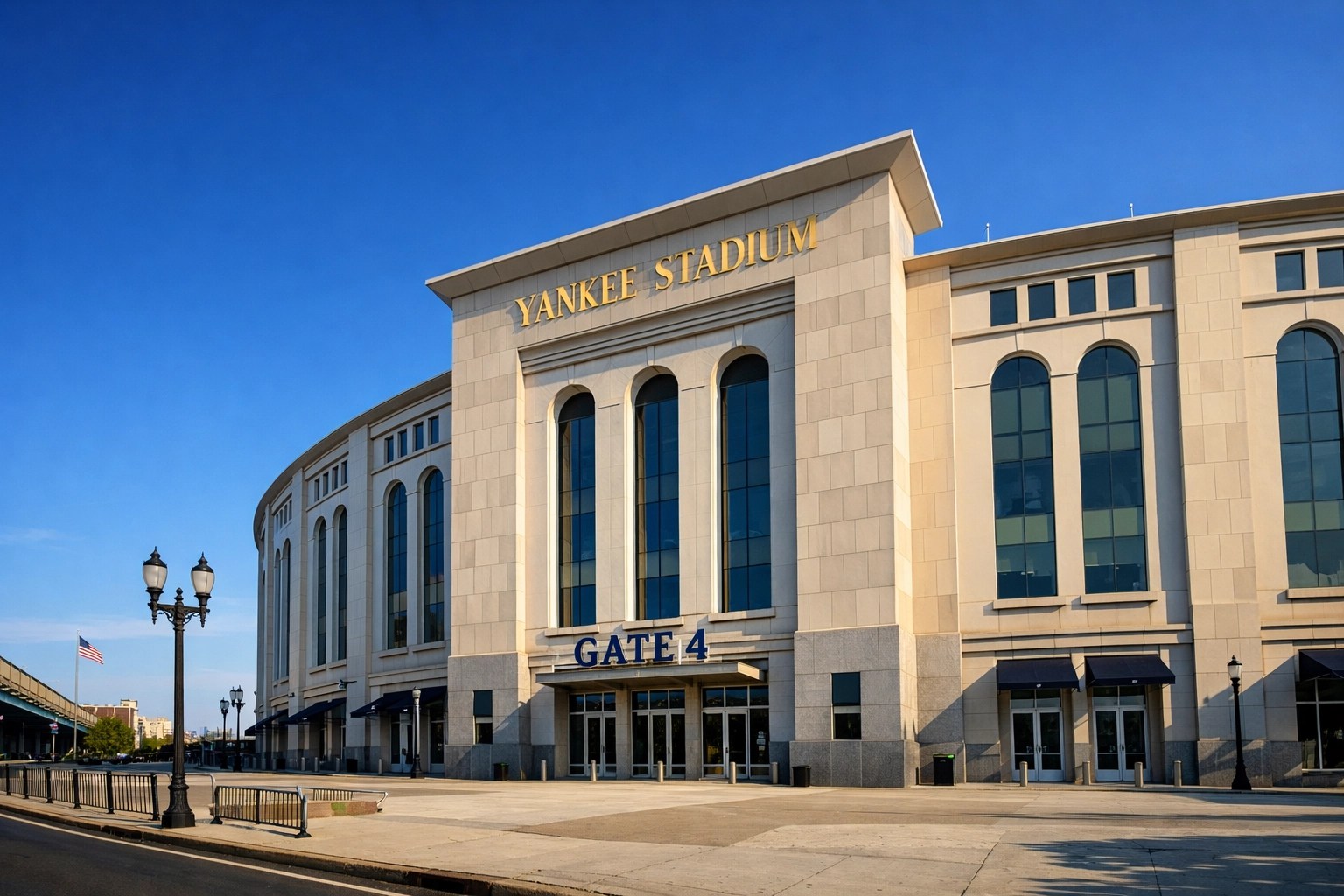 Grand limestone exterior of Yankee Stadium in the Bronx with iconic gold lettering against a clear blue sky.