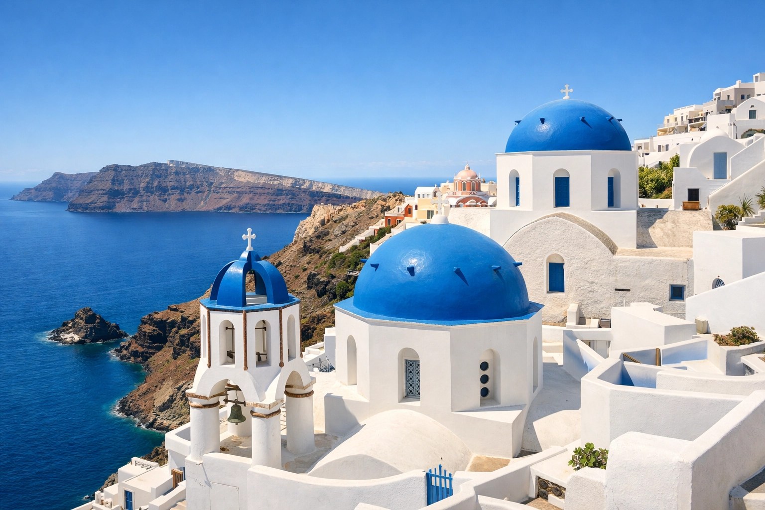 Iconic blue domes in Santorini overlooking the sparkling caldera on a bright, beautiful day.
