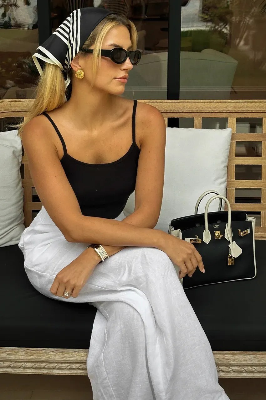 woman wears headscarf trend with black top and white trousers