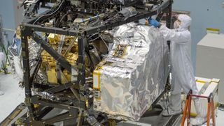Una persona que usa se encuentra al lado de una máquina grande cubierta de papel de aluminio.