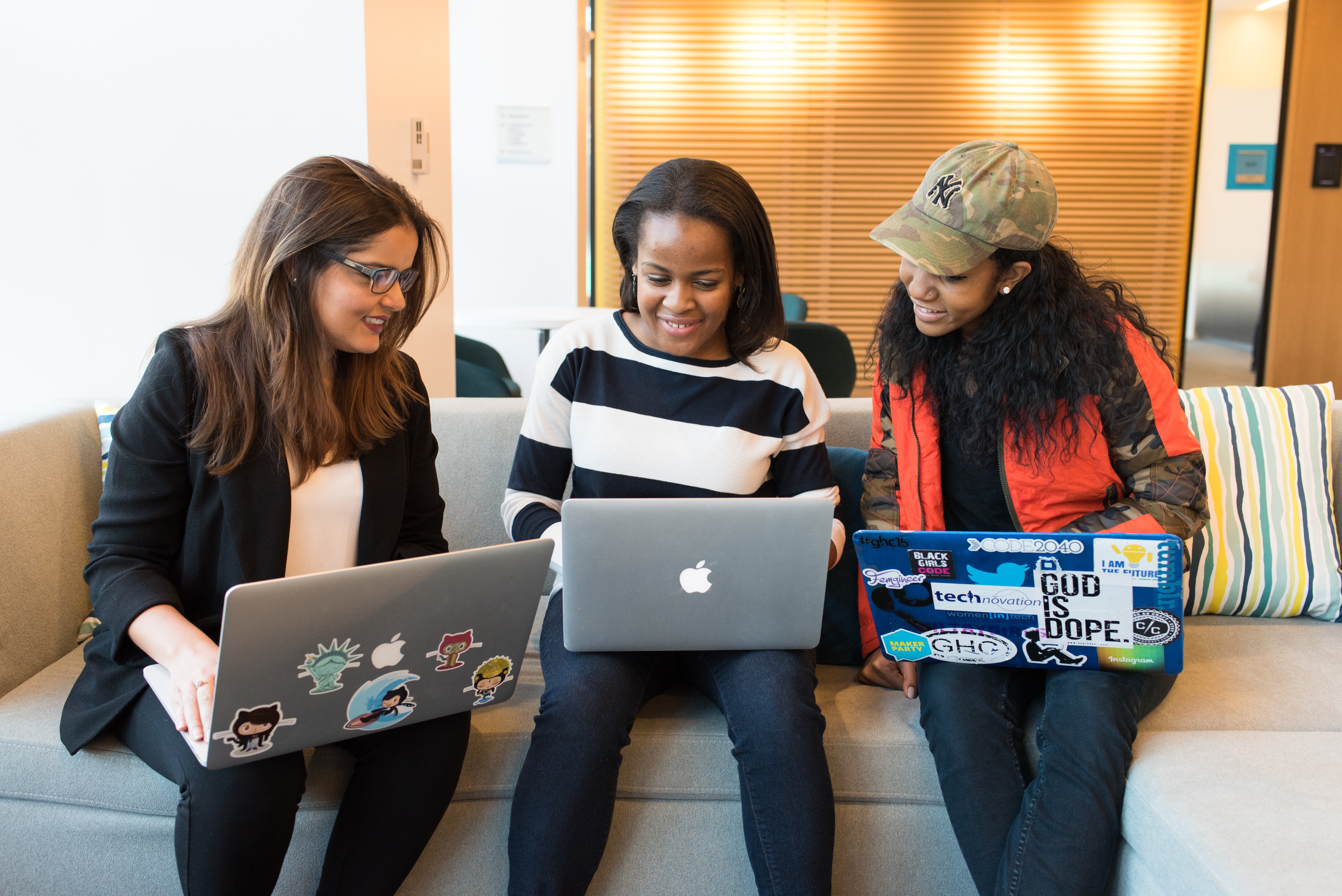 3 women sitting side by side with their laptops