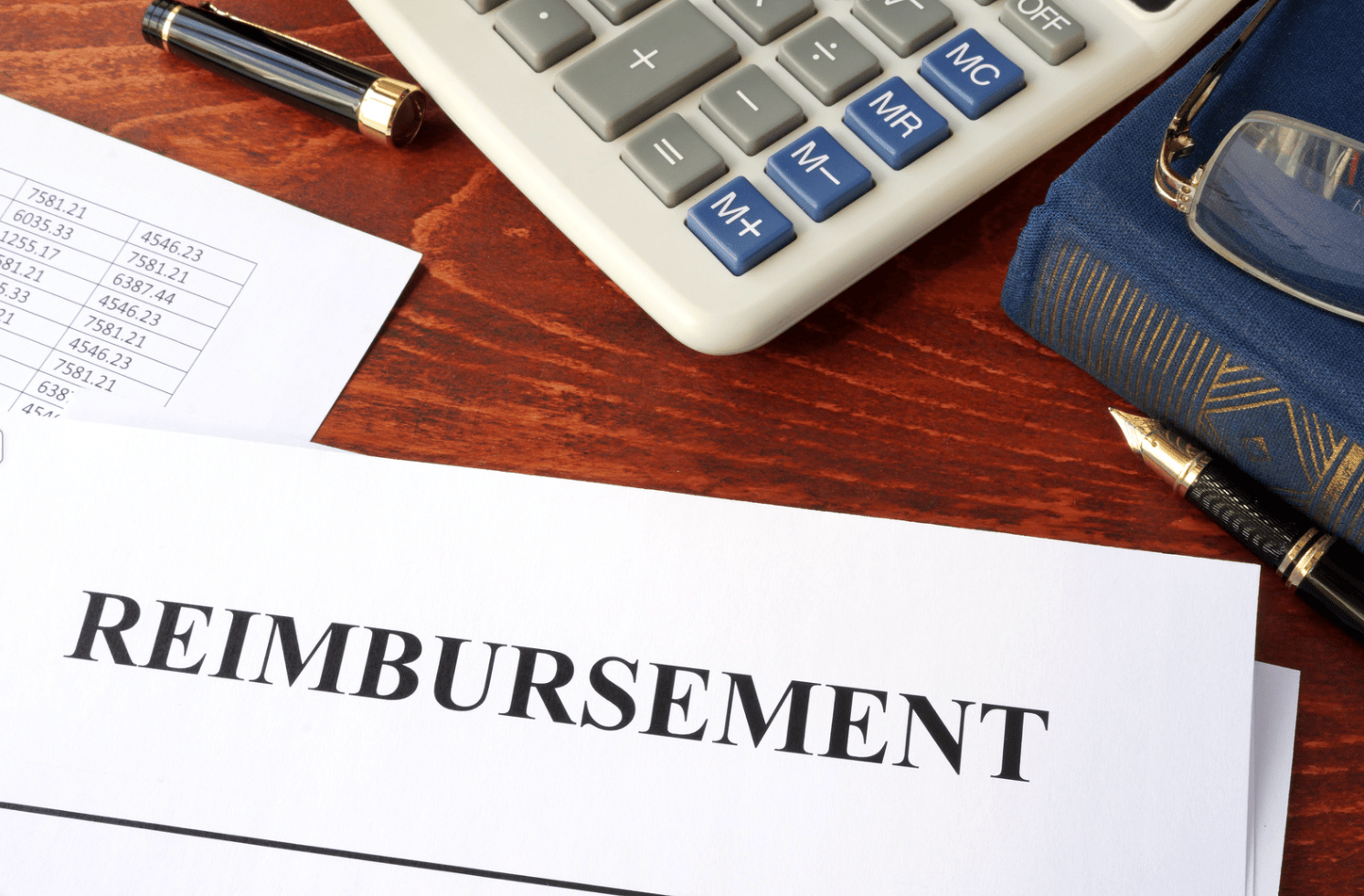 Desk with calculator and paper with text, "reimbursement"