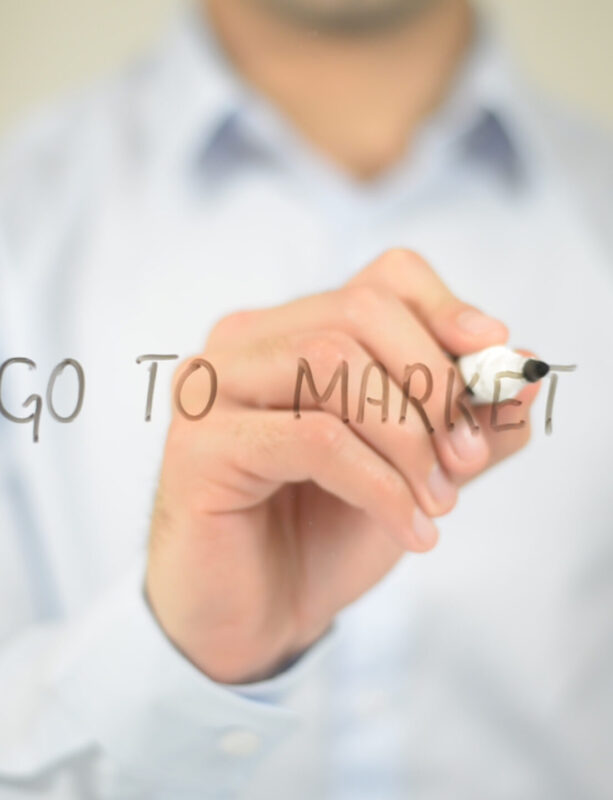 Person writing "Go to Market" on glass.