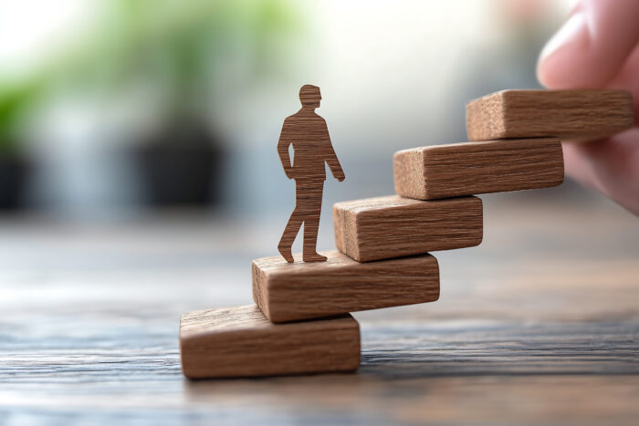 Person climbing stairs made of wooden blocks.