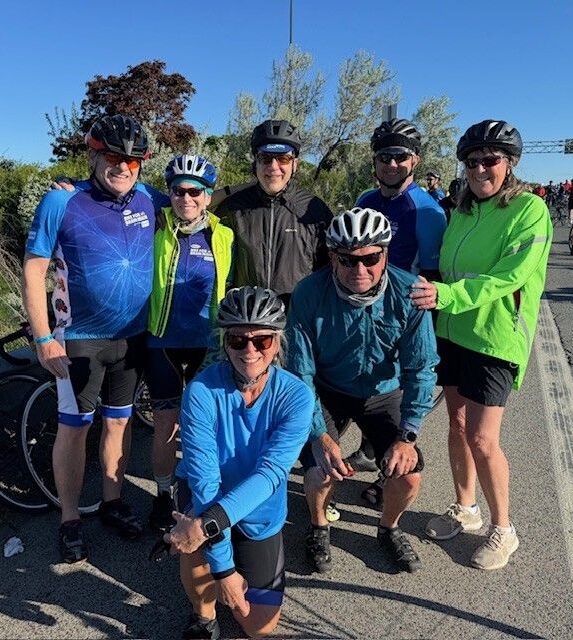 Group of cyclists posing together outdoors.