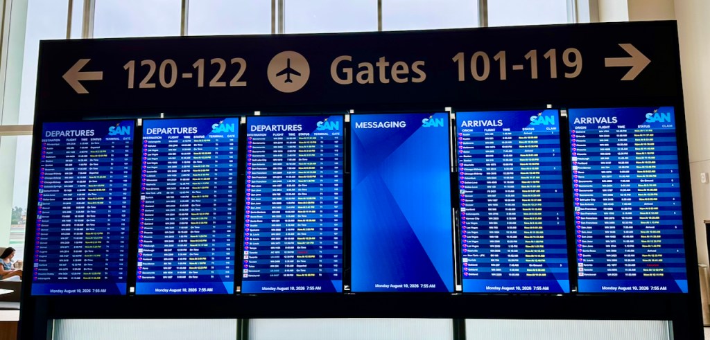 Flight information display board showing departing and arriving flights at an airport, with gates 101-122 and various flight statuses.