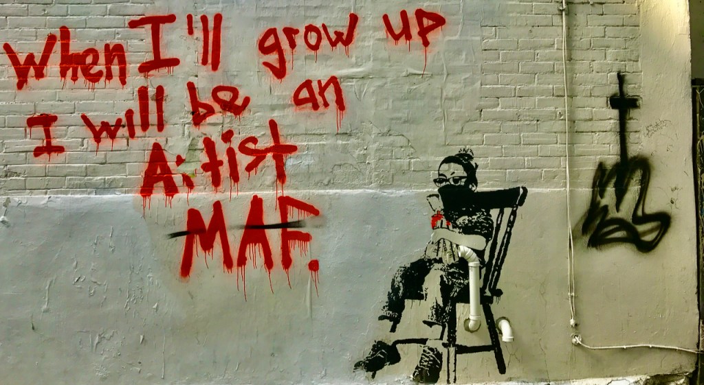 Wall mural featuring a child sitting in a chair, holding a toy, with graffiti text that reads 'When I'll grow up I will be an artist MAF.'