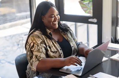 Mulher feliz por ser parceira Certisign, mexendo em um notebook.