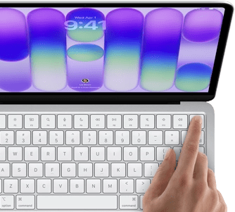 MacBook Neo, silver color, showing login screen, person's finger on Touch ID sensor in top-right corner of keyboard