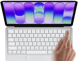 MacBook Neo, silver color, showing login screen, person's finger on Touch ID sensor in top-right corner of keyboard