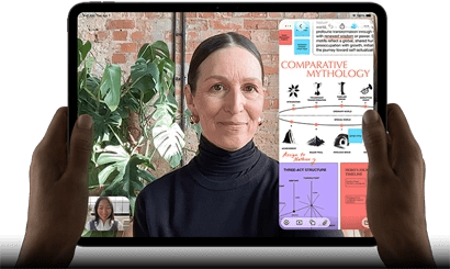 iPad Pro, front exterior, landscape orientation, space black color, rounded corners, black display bezel, hands holding left and right sides, display showing a FaceTime conversation being live translated, and an educational app showing a presentation of "Comparative Mythology" with text, diagrams, and handwritten notes