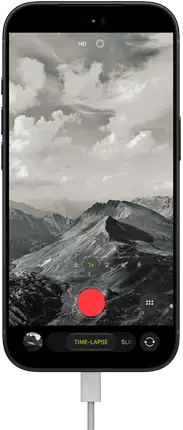 iPhone 18 Pro, front exterior, displaying a mountainous landscape, with the camera mode overlay in Time-Lapse mode, with power cable attached to charging port