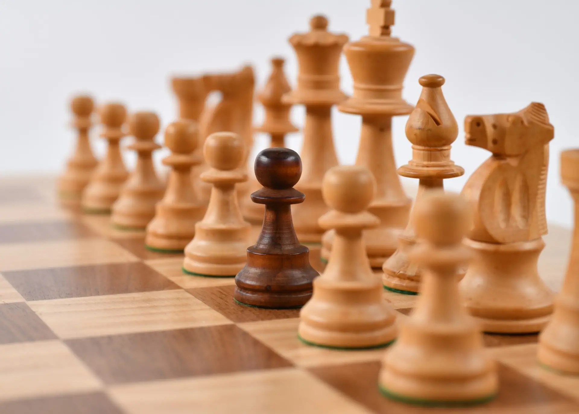 Chessboard showing all white pieces in starting position, with one brown pawn among the white pawns, symbolizing unique leadership