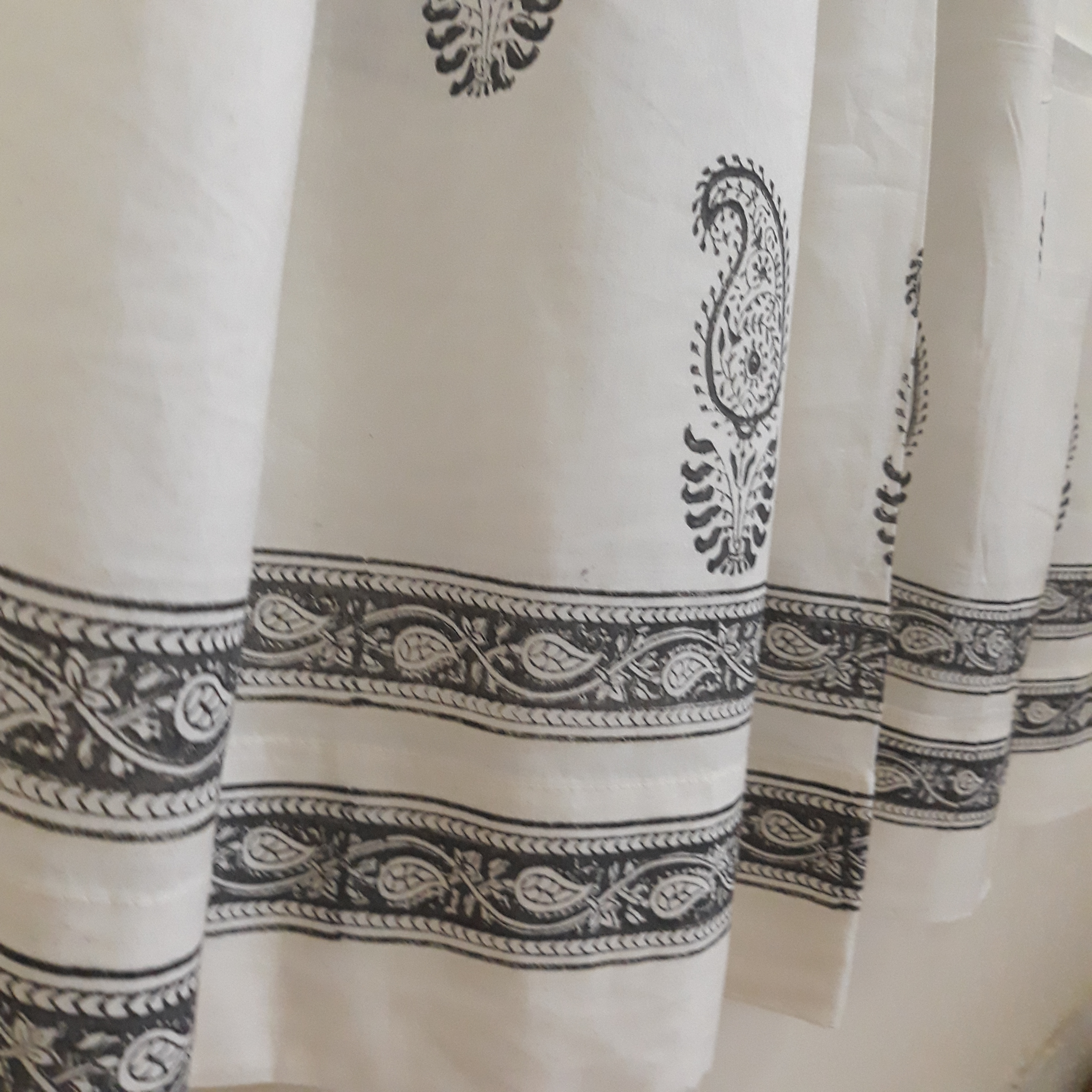 Delicate paisleys block printed on the border of a sheer white cotton decorative window curtain
