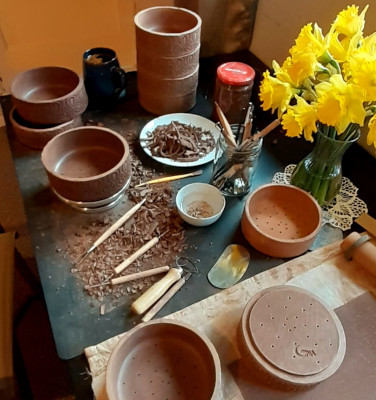 Table with various clay pots, tools and clay shaving showing making of the clay pieces.