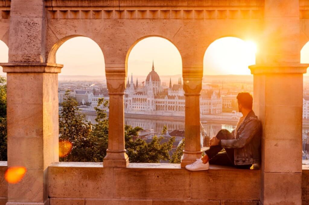 A photograph of a young couple on a road trip, with the man driving and the woman in the passenger seat, looking out at a beautiful, scenic mountain view during a weekend getaway.
