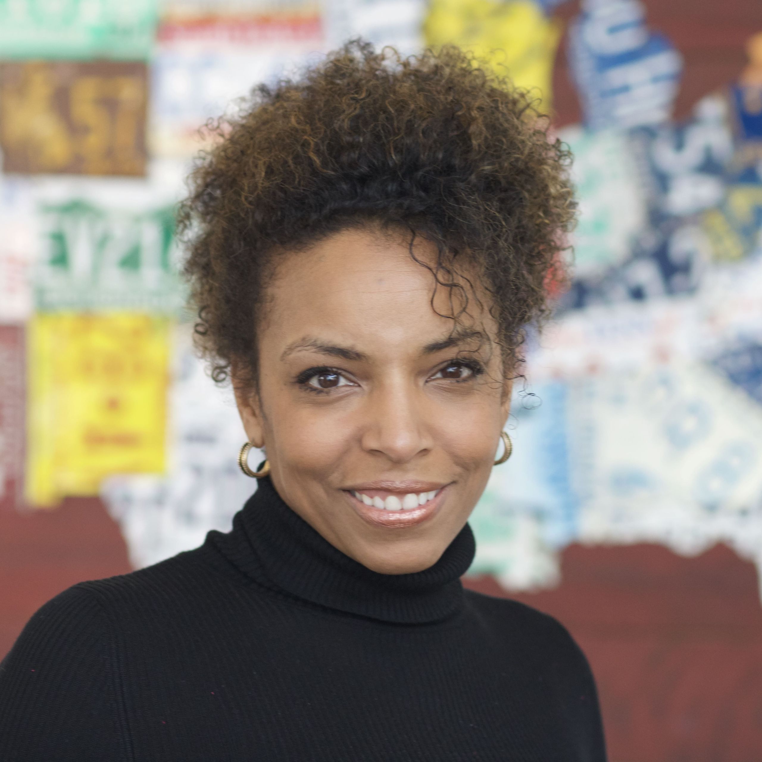 Headshot of Cynthia Overton, a Black woman with natural curly hair swept up and a black turtleneck