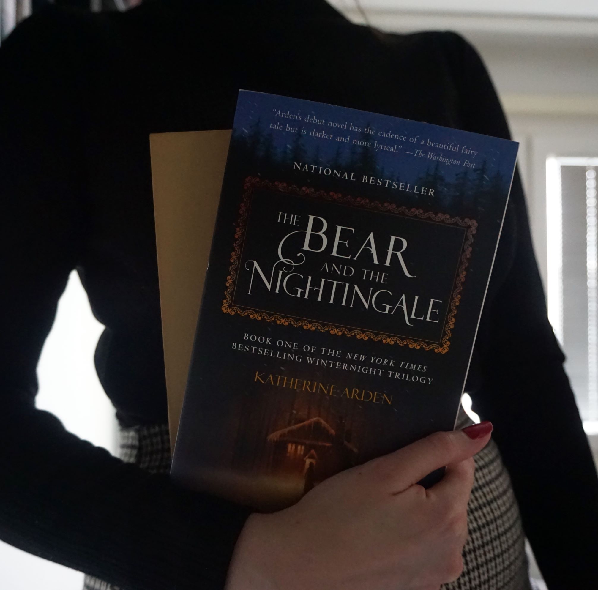 girl holds book The Bear And The Nightingale and beige hardcover book