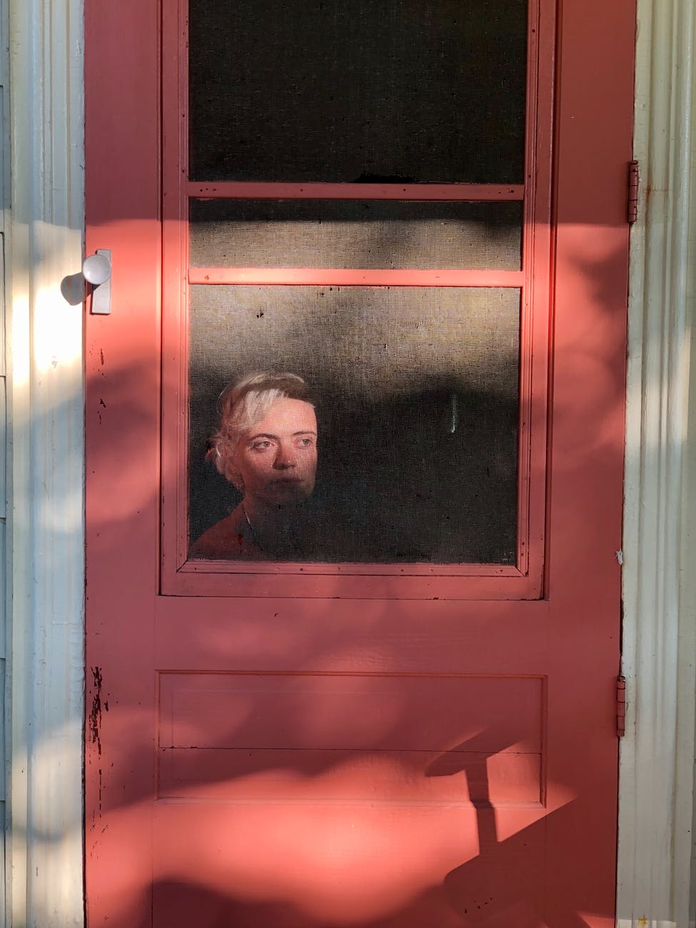young woman sitting behind cottage door and looking away