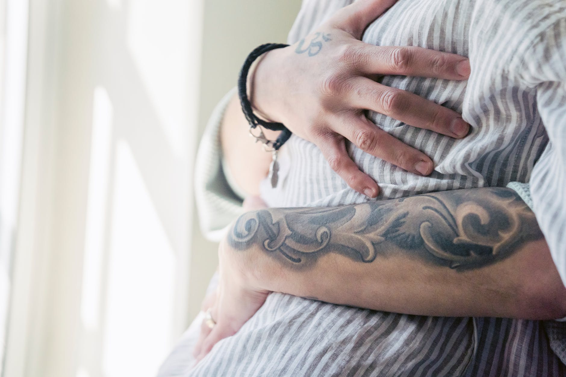 faceless couple with tattoos embracing at home