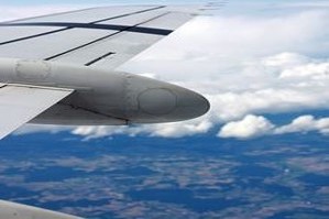 Wing of an airplane flying over a lake