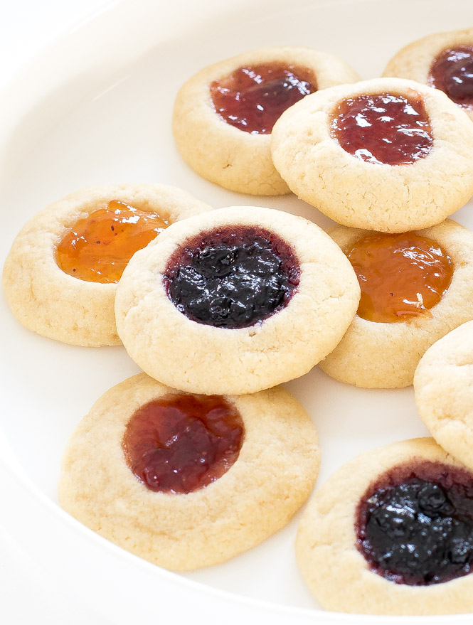 thumbprint cookies filled with different flavors of jam, arrange on a white plate