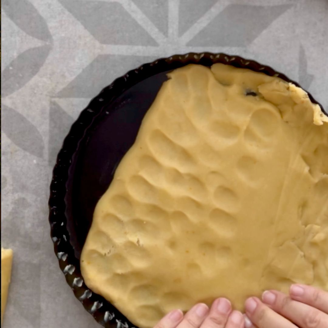 Use your fingers to press the tart dough into the pan.