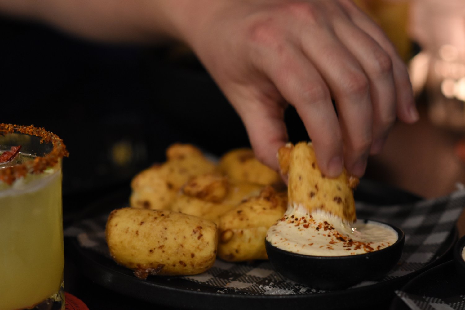 a hand dipping peruvian cheese bread in a creamy sauce at a Mexican restaurant Fitzroy