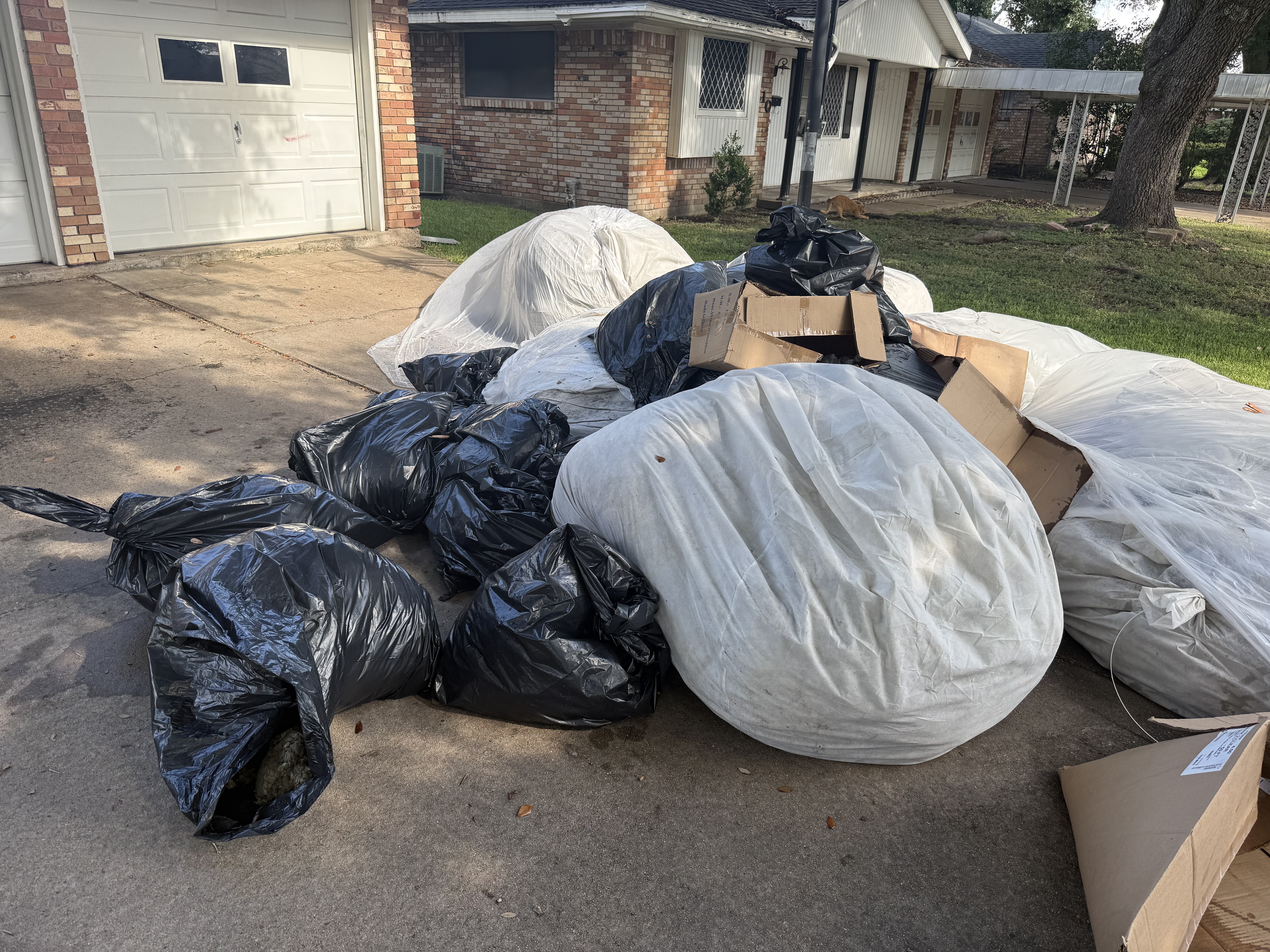 Driveway piled with bagged trash, wrapped mattresses and boxes ready for a full house cleanout