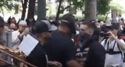 Joey Gibson in tow, Tiny moves up, and forcefully tries to walk into the person.