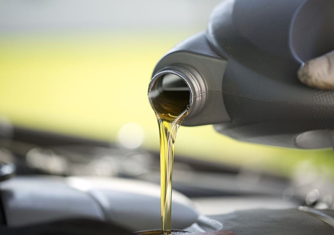 Pouring oil from a gray plastic container into a classic car engine
