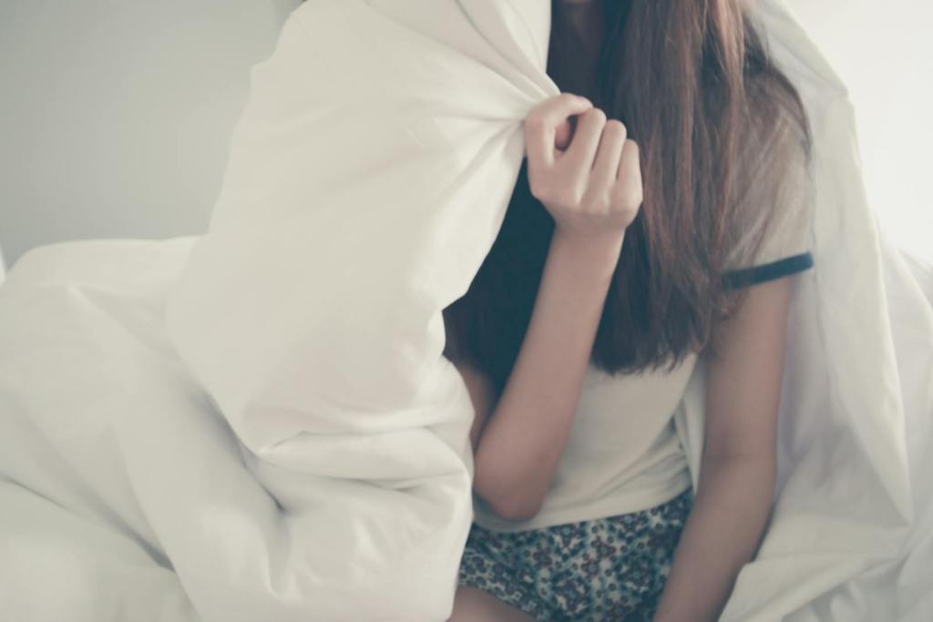 Cozy morning scene with a young woman relaxing under a blanket.