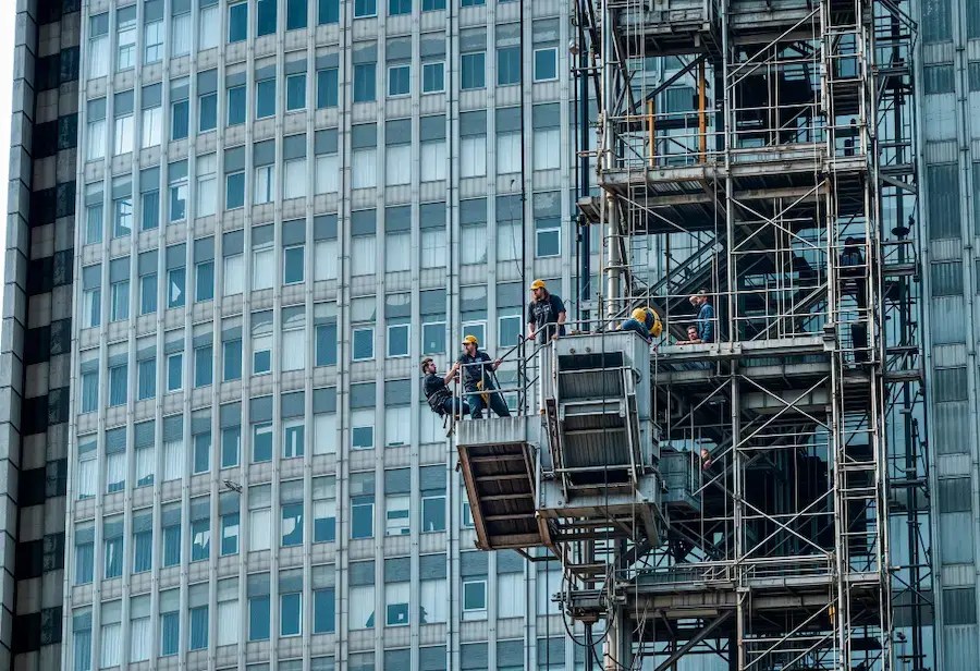 Glass office tower undergoing exterior maintenance and construction work