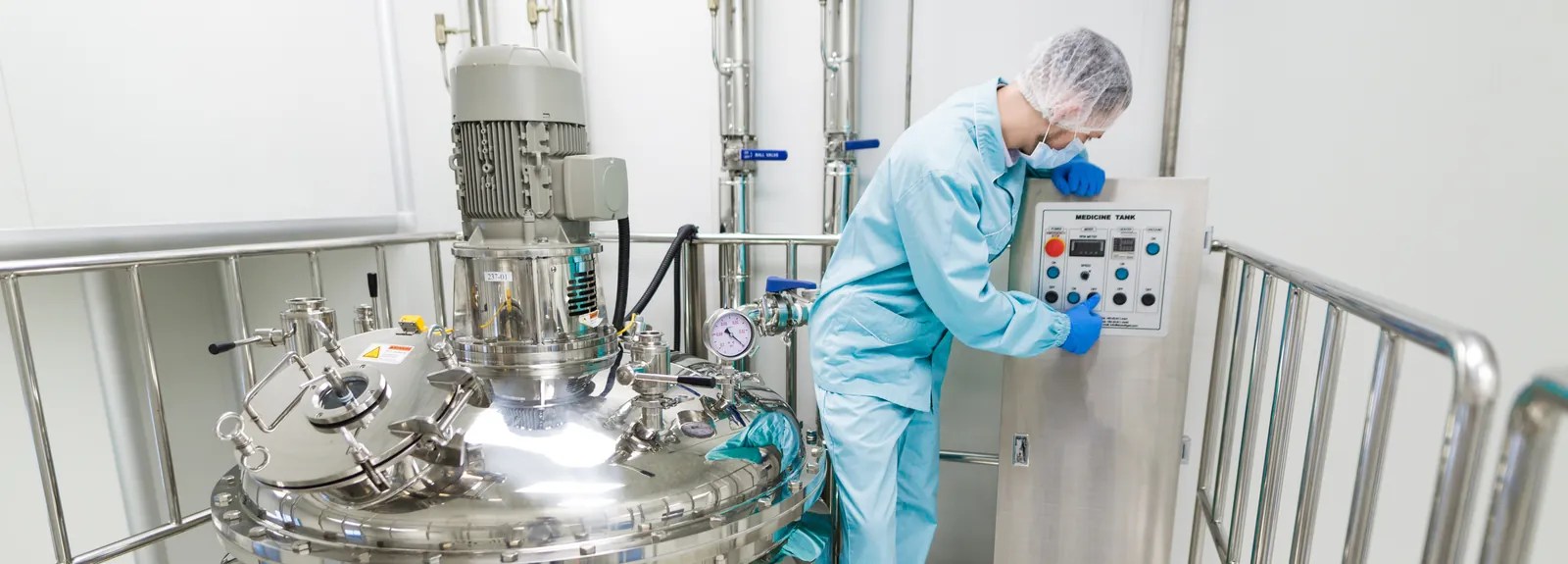 Operator at a stainless steel reactor in a pharmaceutical manufacturing cleanroom