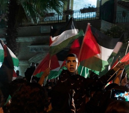 Protesters wave Palestinian flags outside of the family home of veteran journalist Shireen Abu Akleh. (AP)