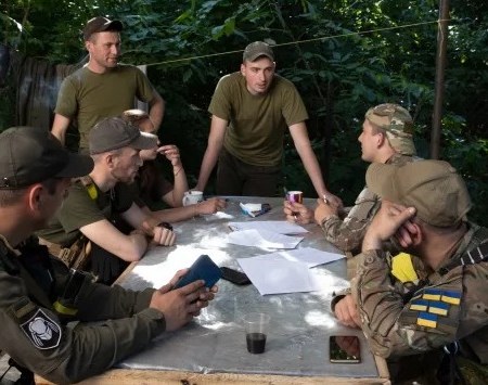 Ukrainian soldiers meet at a base near their aging anti-tank gun just northeast of the Russian-occupied city of Kherson, Ukraine, on Saturday, June 4, 2022. (Tyler Hicks/The New York Times)