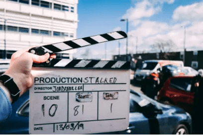 Hand holding a film clapperboard on an outdoor location set to manage a film shooting schedule.